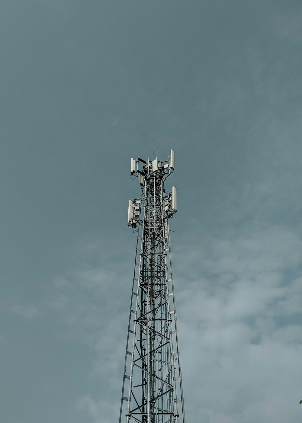 A lattice telecom tower with antennas, against an overcast sky